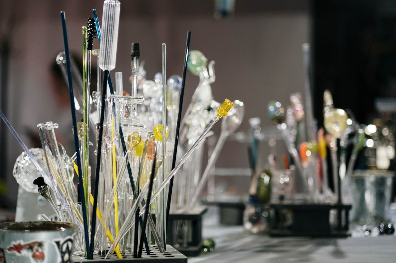 Close-up of assorted glass blowing tools and samples in a workshop.